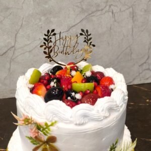 Fresh fruit birthday cake topped with strawberries, kiwi, and berries with whipped cream frosting