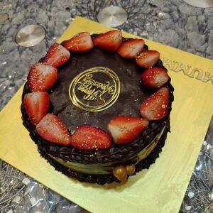 Chocolate cake topped with fresh strawberries and chocolate ganache glaze